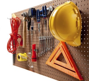 Peg board with hardhat, extension cord, flashlight, hammer, screw driver, caution tape, carpenter's square and pliers