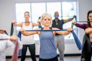 A group of women exercising and using resistance bands during their workout routine. Newbury park storage experts share tips for working out. 