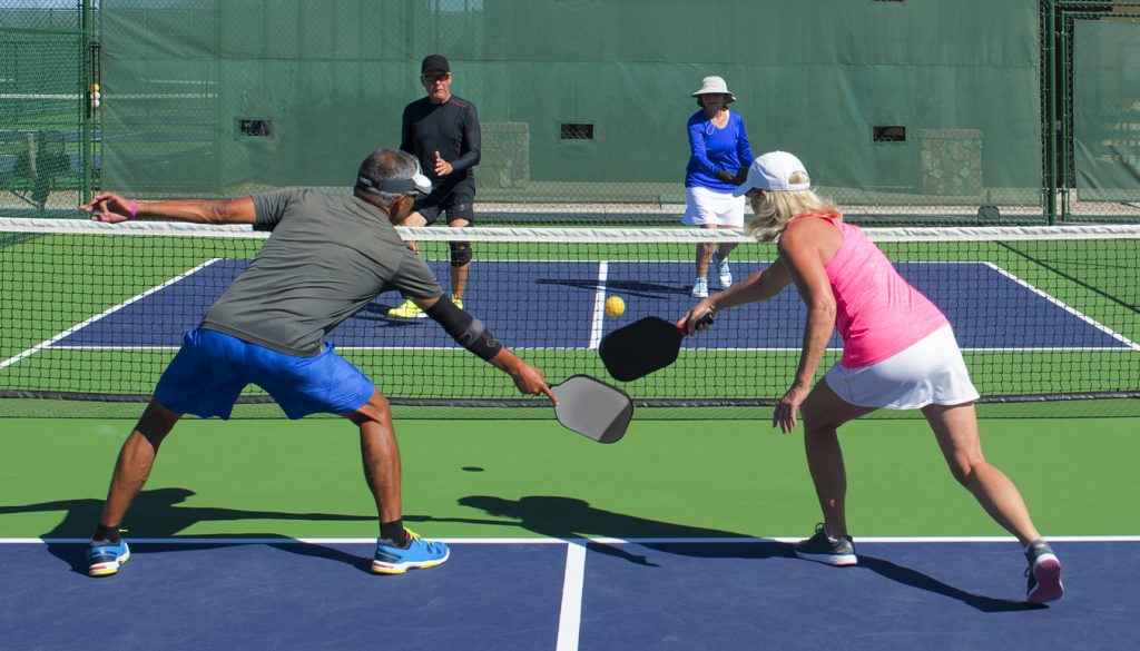 colorful action image of two couples playing pickleball in a mixed doubles match