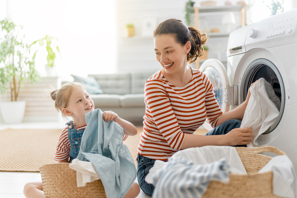 Mom and child looking at each other as they load the washer. Storage Newbury Park experts recommend washing light loads to help the lifespan of your machine. 