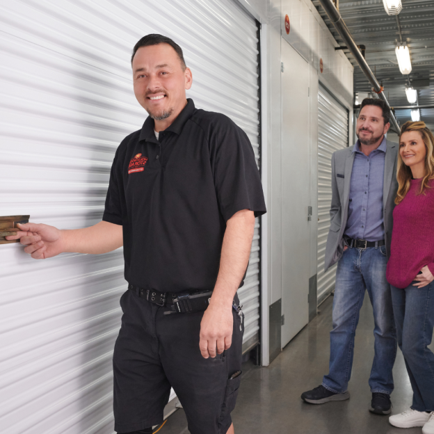 Employee with guests in storage center hallway opening storage gate
