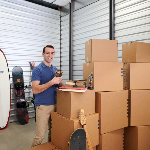 Man in a blue shirt standing in storage unit with boxes